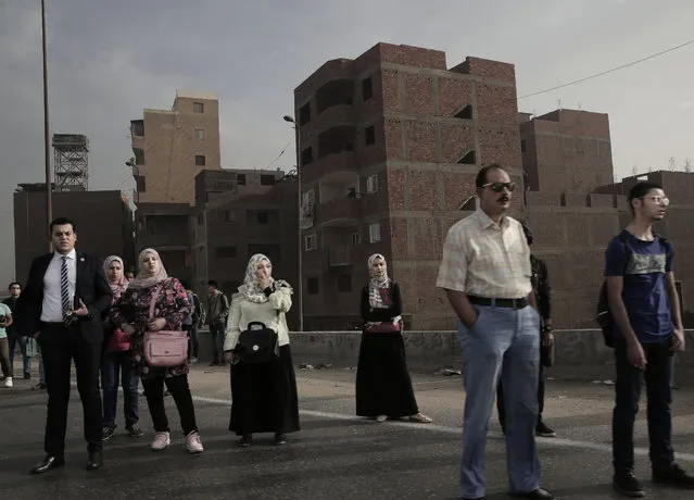 In this October 23, 2018 photo, people wait for an early morning bus on the ring road, in Cairo, Egypt. A city of 20 million people that combines charm and squalor, Cairo may soon witness an exodus by some of its well-heeled residents, state employees and foreign embassies to a new capital. The government argues that Cairo is already bursting at the seams and will grow to 40 million by 2050. (Photo by Nariman El-Mofty/AP Photo)