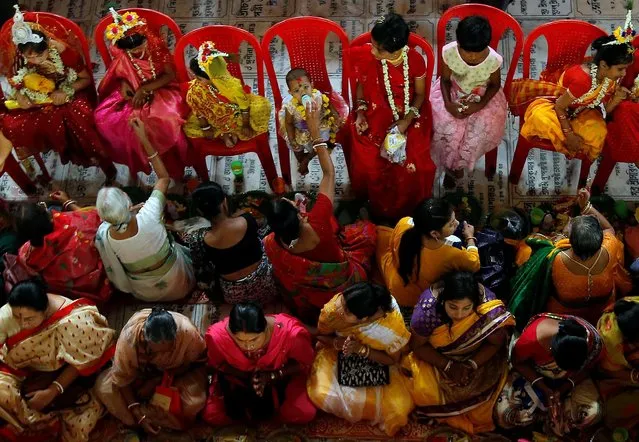 A baby girl is fed as other girls dressed as Kumari are worshipped during rituals to celebrate the Hindu festival of Navratri inside the Adyapeath temple on the outskirts of Kolkata, India, April 14, 2019. (Photo by Rupak De Chowdhuri/Reuters)