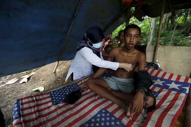 A doctor checks the health of Deden, a teenager whose father says suffers from mental illness and lives chained to a tree under a shelter next to a rice paddy near his family home in Longkewang village in Serang, Banten province, Indonesia  March 23, 2016. (Photo by Reuters/Beawiharta)