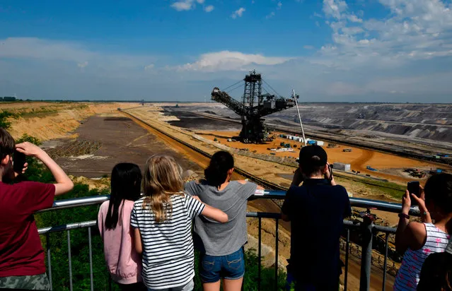 Visitors take a picture of a bucket-wheel excavator used to dig brown coal at the Garzweiler lignite mine near Jackerath, Germany on June 18, 2019. Thousands of climate activists are preparing to blockade the site. (Photo by Ina Fassbender/AFP Photo)