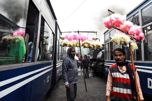 Vendors sell candy floss to passengers as Darjeeling Himalayan Railway trains, which runs on a 2 foot gauge railway and is a UNESCO World Heritage Site, arrive at a station in Ghum, India, June 25, 2019. (Photo by Ranita Roy/Reuters)