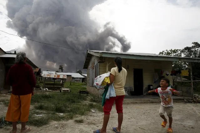 A child reacts as ash spews from Mount Sinabung volcano during an eruption as seen from Kuta Tengah village in Karo Regency, North Sumatra province, Indonesia June 26, 2015. (Photo by Reuters/Beawiharta)
