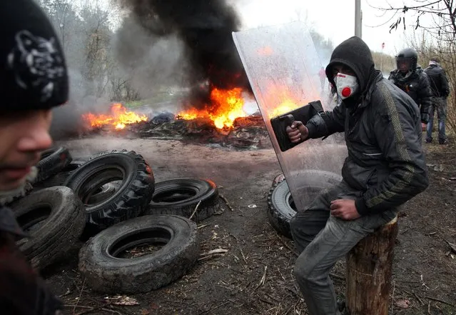 Pro-Russian protesters burn tires as they prepare for battle with the Berkut (Ukrainian special police forces) on the outskirts of the eastern Ukrainian city of Slavyansk on April 13, 2014. Ukraine's interior minister said on April 13 that both sides had suffered casualties during a raid launched by Ukrainian special forces on a police station in the eastern city of Slavyansk that was seized by pro-Russian gunmen. (Photo by Anatoliy Stepanov/AFP Photo)