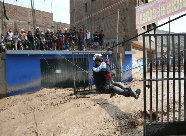 Agents of the Peruvian National Police rescue people trapped in buildings due to the flooding of the Rimac and Huaycoloro rivers, in Lima, Peru, 17 March 2017. In Lima, two people have died and 2739 inhabitants have been displaced due to the floodings, according to a report by the National Emergency Operations Center. (Photo by Ernesto Arias/EPA)
