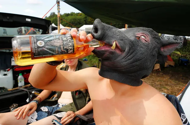 A festival goer from the Bavarian town of Diessen near Munich wears a pig mask as he drinks sweet mead, the official mead of the world's largest heavy metal festival, the Wacken Open Air 2019, in Wacken, Germany on August 3, 2019. (Photo by Wolfgang Rattay/Reuters)