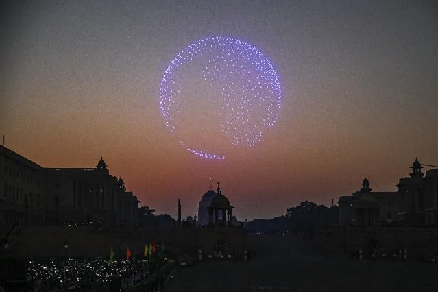 Spectators use their mobile phones as drones with lights fly over the Presidental Palace during the 'Beating Retreat' ceremony in New Delhi on January 29, 2022. (Photo by Prakash Singh/AFP Photo)