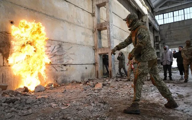 A local resident throws a Molotov cocktail against a wall during an all-Ukrainian training campaign “Don't panic! Get ready!” close to Kyiv, Ukraine, Sunday, February 6, 2022. Russia has denied any plans of attacking Ukraine, but urged the U.S. and its allies to provide a binding pledge that they won't accept Ukraine into NATO, won't deploy offensive weapons, and will roll back NATO deployments to Eastern Europe. Washington and NATO have rejected the demands. (Photo by Efrem Lukatsky/AP Photo)