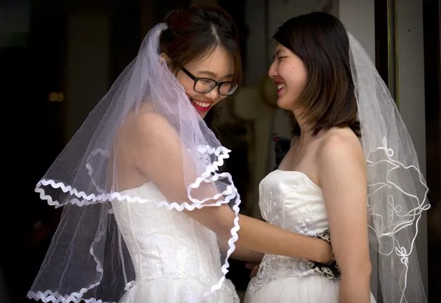 Teresa Xu, left, and Li Tingting, right, share a moment outside of a beauty salon where the two were preparing for their wedding in Beijing, Thursday, July 2, 2015. A prominent Chinese lesbian couple held a simple ceremony Thursday to announce their informal marriage, in their latest effort to push for legalization of same-s*x unions in China. (Photo by Mark Schiefelbein/AP Photo)