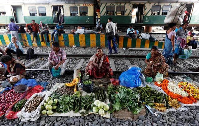 Street sellers sit between railway tracks waiting for customers to arrive on passing trains in Kolkata, India on March 24, 2017. (Photo by Rupak de Chowdhuri/Reuters)