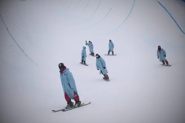 Volunteers inspect the halfpipe course before the men's halfpipe qualification at the 2022 Winter Olympics, Thursday, February 17, 2022, in Zhangjiakou, China. (Photo by Francisco Seco/AP Photo)