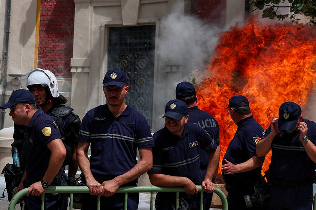 Police officers react as supporters of the opposition hurl Molotov cocktails at the mayor's office accusing him of corruption in Tirana, Albania, on May 21, 2024. (Photo by Florion Goga/Reuters)