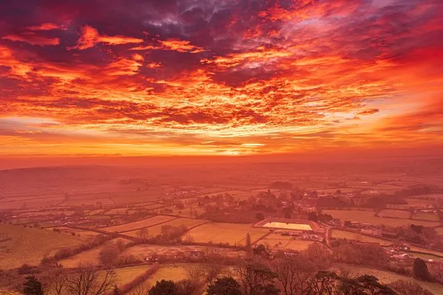 Visitors who pick the right morning to climb the 158m Glastonbury Tor are rewarded with 360-degree views of the sun rising over Somerset on December 21, 2021. The Tor has long been a spiritual magnet and, according to Celtic myth, there is a cave hidden under the hill that leads to the fairy realm of Annwn. (Photo by Annwn Michelle Cowbourne/South West News Service)