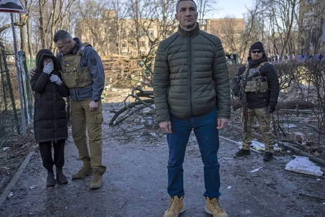 Ukrainian former heavyweight boxing world champion Wladimir Klitschko, center, looks on as his brother Kyiv Mayor, Vitali Klitschko, left, comforts a neighbor who cries at the site where a bombing damaged residential buildings in Kyiv, Ukraine, Friday, March 18, 2022. Russian forces pressed their assault on Ukrainian cities Friday, with new missile strikes and shelling on the edges of the capital Kyiv and the western city of Lviv, as world leaders pushed for an investigation of the Kremlin's repeated attacks on civilian targets, including schools, hospitals and residential areas. (Photo by Rodrigo Abd/AP Photo)