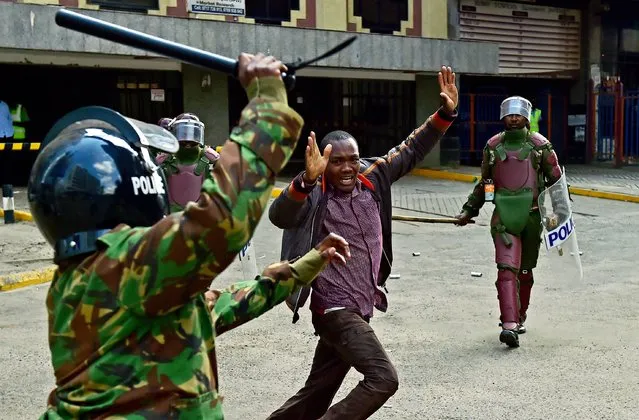 Kenyan riot police officers raise batons over a man during a demonstration of Kenya's opposition supporters in Nairobi, on May 16, 2016. Opposition protestors led by former Prime Minister Raila Odinga gathered outside the Indepedent Electoral and Boundaries Comission building to demand the dismissal of IEBC commissioners, after alleged bias towards the ruling Jubillee Alliance Party. (Photo by Carl De Souza/AFP Photo)