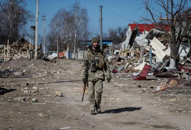 A Ukrainian service member walks, as the Russian invasion continues, in a destroyed village on the front line in the east Kyiv region, Ukraine on March 21, 2022. (Photo by Gleb Garanich/Reuters)