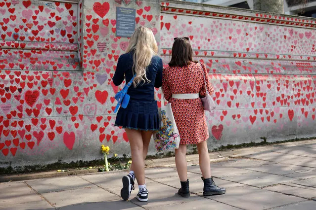 Pedestrians stop to look at the National Covid Memorial Wall in London on March 23, 2022 as Britain held a minute's silence to remember the victims of the coronavirus pandemic, on the second anniversary of the country's first lockdown. (Photo by Tolga Akmen/AFP Photo)