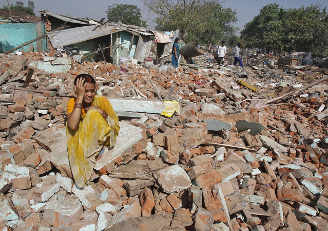 A slum dweller cries after her house was demolished by local authorities at a slum area in the northern Indian city of Chandigarh May 10, 2014. Authorities claimed that the houses in the area were illegally built. (Photo by Ajay Verma/Reuters)