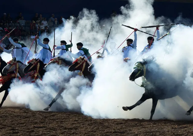 A troupe charges and fire their rifles loaded with gunpowder during a national competition for Tabourida,salon du cheval d'el jadida, in El Jadida, Morocco, 15 October 2019. (Photo by Jalal Morchidi/EPA/EFE)