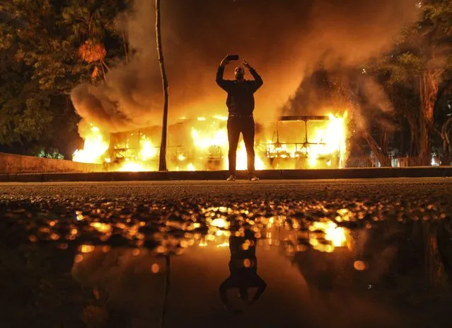 A man takes a selfie in front as protesters burn buses during a strike in Rio de Janeiro, Brazil, 28 April 2017. Throughout the country Brazilian unions backed by various social movements and indigenous tribes are striking against pension and labor reforms being pushed by the conservative government of President Michel Temer. (Photo by Antonio Lacerda/EPA)