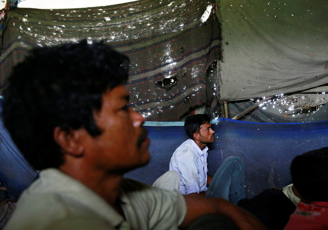 People watch a movie in a makeshift cinema located under a bridge in the old quarters of Delhi, India May 25, 2016. (Photo by Cathal McNaughton/Reuters)