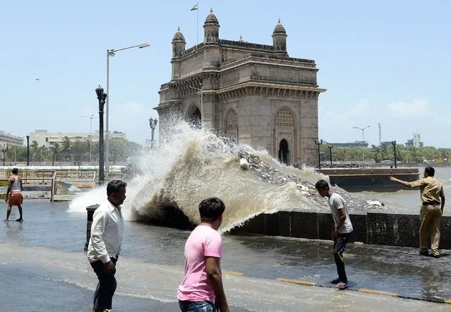 An Indian policeman (R) warns onlookers as waves come ashore during high tide near the Gateway of India  in Mumbai on June 13, 2014. The Indian Meteorological Department (IMD) has declared the start of the monsoon season, predicting below-average rainfall. The monsoon season, which runs from June to September, accounts for about 80 percent of India's annual rainfall, vital for a farm economy which lacks adequate irrigation facilities. (Photo by Indranil Mukherjee/AFP Photo)