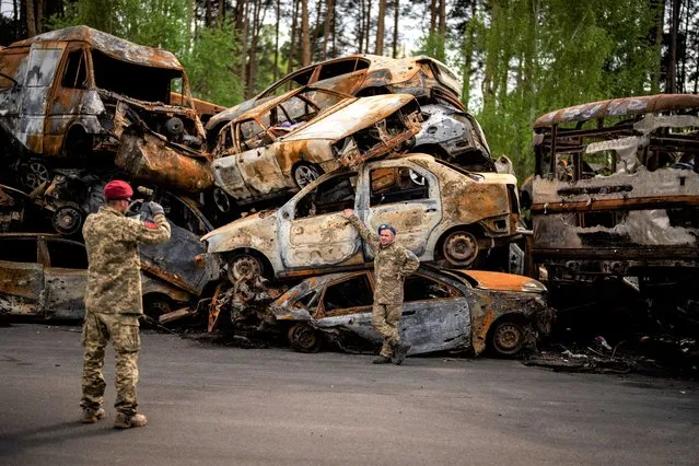 A territorial defence man poses for a photo next to cars destroyed during the Russian occupation in Irpin, on the outskirts of Kyiv, on Saturday, May 7, 2022. (Photo by Emilio Morenatti/AP Photo)