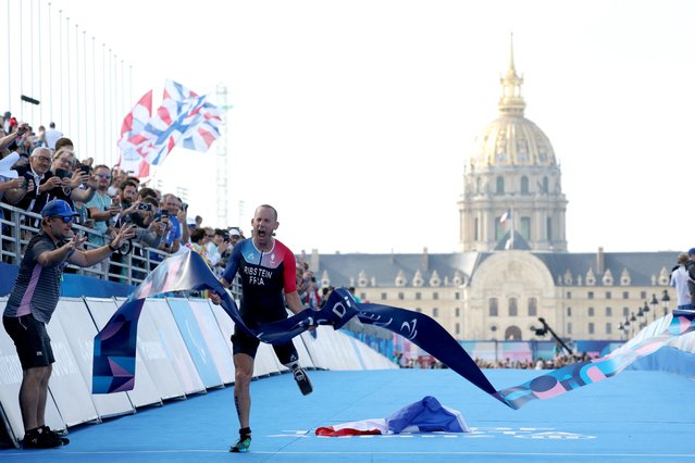 France's Jules Ribstein celebrates as he crosses the finish line to win the men's PTS2 para triathlon event at the Paris 2024 Paralympic Games at the Pont Alexandre III on September 2, 2024. (Photo by Alain Jocard/AFP Photo)