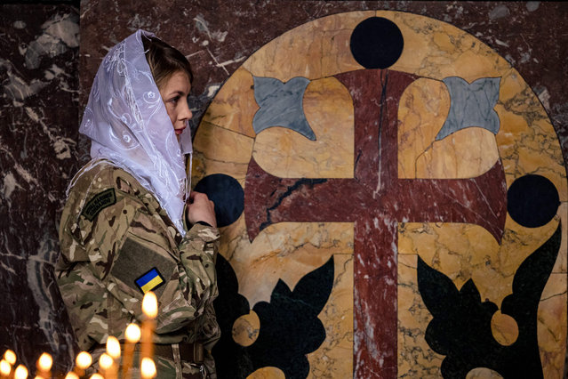 A female Ukrainian soldier crosses herself during an Orthodox Easter service in St. Volodymyr's Cathedral in Kyiv on April 24, 2022, two months after the start of Russia's invasion of Ukraine. (Photo by Dimitar Dilkoff/AFP Photo)