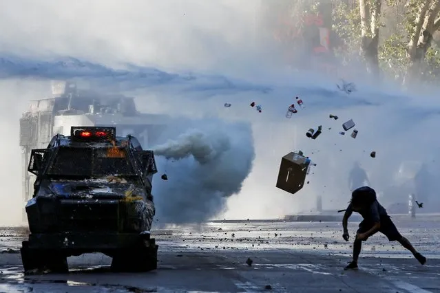 A demonstrator throws items at an armoured vehicle during a protest against Chile's government in Santiago, Chile on December 30, 2019. (Photo by Ivan Alvarado/Reuters)