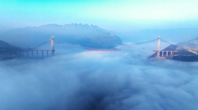 Workers are hoisting a steel girder of the main bridge in the clouds at the Zangke River Bridge on the expressway in Bijie, Guizhou Province, China, on December 12, 2023. The main span of the Zangke River Bridge is 1,080 meters long, and the bridge floor is 380 meters above the river surface. (Photo by Costfoto/NurPhoto via Getty Images)