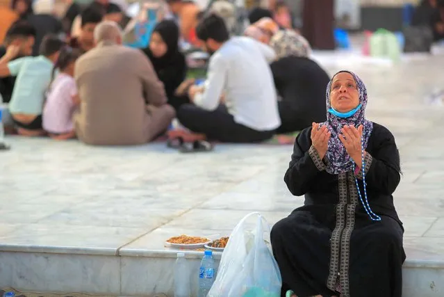 A woman prays before eating the Iftar, the meal to end their fast at sunset, during the holy fasting month of Ramadan at the shrine of cleric Sheikh Abdul Qadir al-Gailani in Baghdad, Iraq on April 27, 2022. (Photo by Thaier Al-Sudani/Reuters)