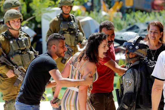 A Palestinian woman argues with an Israeli border policewoman over the Israeli demolition of a building housing an apartment and a restaurant as the building owners said they were informed by the forces that they did not obtain a construction permit, in Beit Jala in the Israeli-occupied West Bank on August 26, 2019. (Photo by Mussa Qawasma/Reuters)