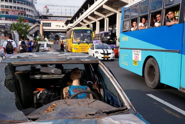 Bus passengers look out at a mock vehicle to be used in a simulated earthquake aftermath, before the start of a metrowide earthquake drill along main highway EDSA in Makati, Metro Manila, Philippines June 22, 2016. (Photo by Erik De Castro/Reuters)