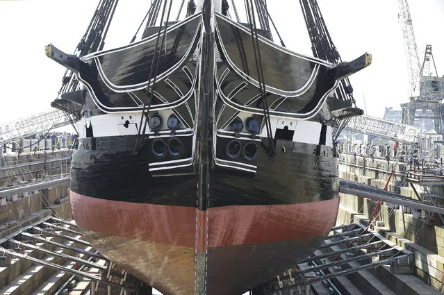 In this Monday, July 17, 2017 photo Bob Gerosa, the 74th Commander of USS Constitution, “Old Ironsides”, the world's oldest commissioned warship still afloat, stands beside the vessel while it sits in dry dock in Boston after a more then two year long restoration. The ship is scheduled to be refloated overnight Sunday July 23, 2017 and be docked back at its berth Monday morning. (Photo by Stephan Savoia/AP Photo)