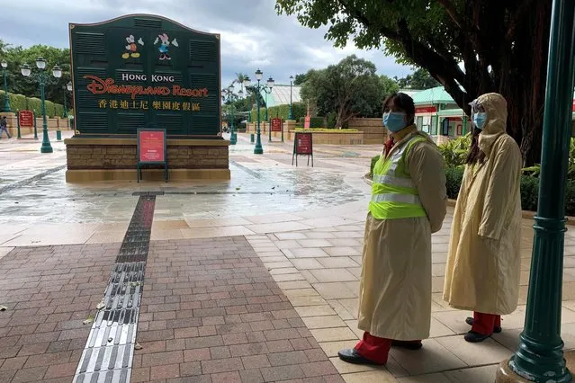 Employees wearing protective masks stand outside the Hong Kong Disneyland theme park that has been closed due to the coronavirus outbreak, January 26, 2020. (Photo by James Pomfret/Reuters)