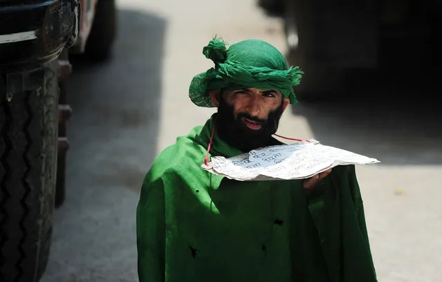 A beggar waits for alms as Indian Muslims offer prayers on the last congregational Friday prayers of the holy month of Ramadan, on a street outside the Jama Masjid in Allahabad on July 1, 2016. Muslim devotees took part in the last Friday prayers ahead of the Eid al-Fitr festival marking the end of the fasting month of Ramadan, which is dependent on the sighting of the moon. (Photo by Sanjay Kanojia/AFP Photo)