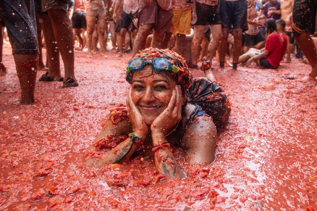 A tourist lies down on the tomato and water soup that has formed on August 30, 2023 in Bunol, Spain. Spain's tomato throwing party in the streets of Bunol, Valencia brings together almost 20,000 people, with some 150,000 kilos of tomatoes thrown each year, this year with a backdrop of high food prices affected by Spain's historic drought. (Photo by Zowy Voeten/Getty Images)