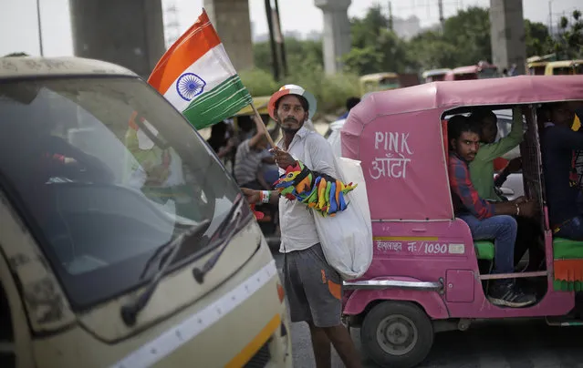 An Indian street hawker sells Indian tricolor flags and other merchandise at a traffic intersection on Independence Day in New Delhi, India, Tuesday, August 15, 2017. (Photo by Altaf Qadri/AP Photo)