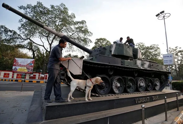 Members of a bomb disposal squad from Gujarat Police scan a tank, which is on display outside an army camp, on a roadside along a route that U.S. President Donald Trump and India's Prime Minister Narendra Modi will be taking during Trump's upcoming visit, in Ahmedabad, February 18, 2020. (Photo by Amit Dave/Reuters)
