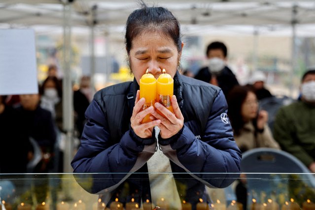 A mother holds candles as she prays for her child's success in the annual College Scholastic Ability Test, at a Buddhist temple in Seoul, South Korea on November 14, 2024. (Photo by Kim Soo-Hyeon/Reuters)