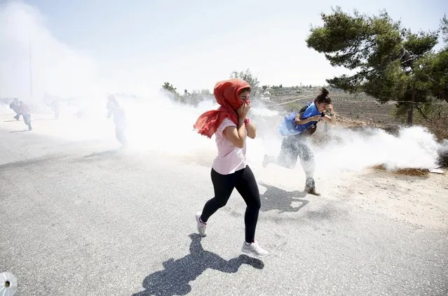 Protesters react as they run away from tear gas fired by Israeli troops during clashes at a protest against Jewish settlements in the West Bank village of Nabi Saleh, near Ramallah August 21, 2015. (Photo by Mohamad Torokman/Reuters)