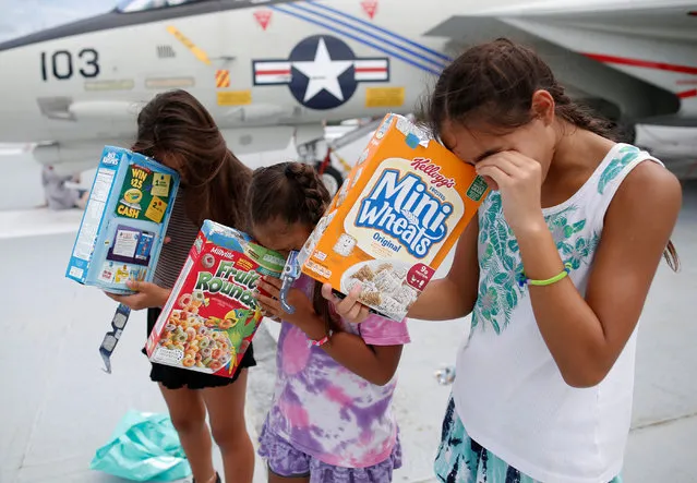 Michelle Campano (Right) and her sisters Jennifer (Middle) and Lauren Campano, all of Rockville, Maryland, check on the position of the sun using homemade solar viewers from the flight deck of the Naval museum ship U.S.S. Yorktown during the Great American Eclipse in Mount Pleasant, South Carolina on August 21, 2017. (Photo by Randall Hill/Reuters)