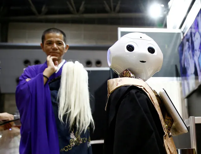 A Buddhist monk looks at a “robot priest” wearing a Buddhist robe during its demonstration at Life Ending Industry EXPO 2017 in Tokyo, Japan August 23, 2017. (Photo by Kim Kyung-Hoon/Reuters)