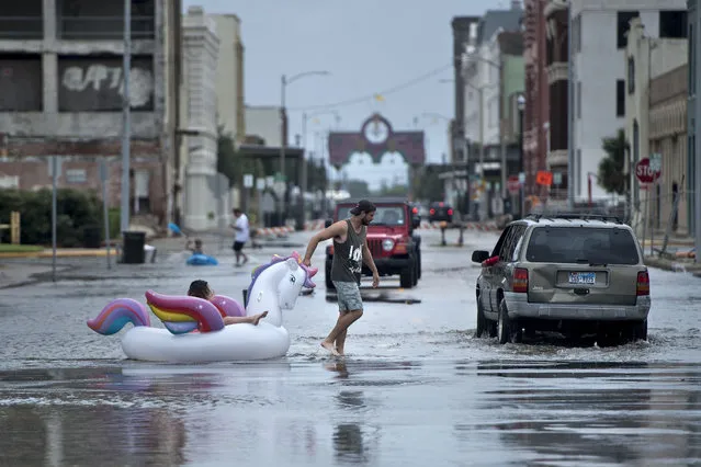 People make their way down partially flooded roads following the passage of Hurricane Harvey on August 26, 2017 in Galveston, Texas. (Photo by Brendan Smialowski/AFP Photo)