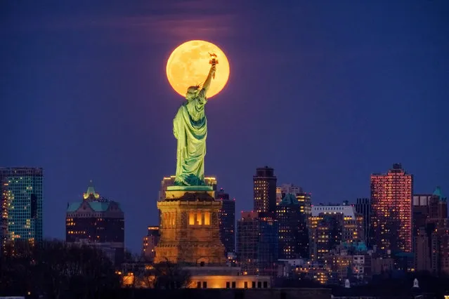 The rising full moon crosses behind the Statue of Liberty, Monday evening, March 9, 2020, in New York City. (Photo by J. David Ake/AP Photo)