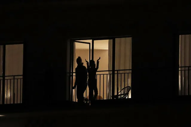 People applaud the caregivers for their work, as the coronavirus ravaged communities across the country, in Ville d'Avray, outside Paris, Thursday, March 19, 2020. In France at 8pm sharp local time French citizens leaned out of windows and dangled from balconies and began applauding and whistling in unison to thank those on the front lines of the pandemic that has already claimed scores of lives. (Photo by Christophe Ena/AP Photo)