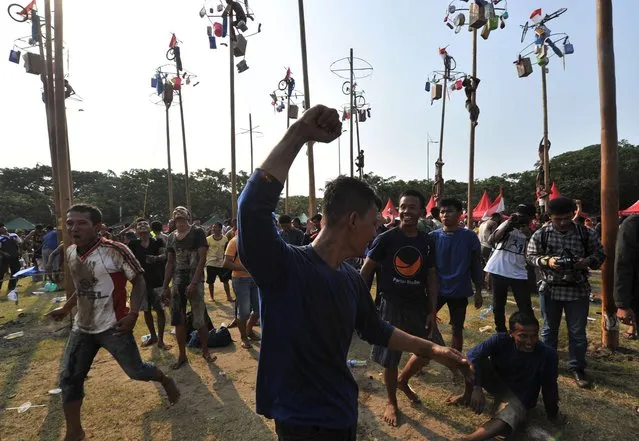 A team celebrates after claiming all the prizes in a local competition called “panjat pinang” in which they had to be the first to climb a greased pole and reach the top, during an event to celebrate Indonesia's Independence Day in Jakarta on August 17, 2014. (Photo by Adek Berry/AFP Photo)