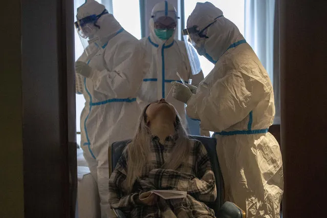 A woman takes a COVID-19 test at a quarantine hotel in Wuhan in central China's Hubei province on Tuesday, March 31, 2020. China on Tuesday reported just one new death from the coronavirus and a few dozen new cases, claiming that all new cases came from overseas. (Photo by Ng Han Guan/AP Photo)