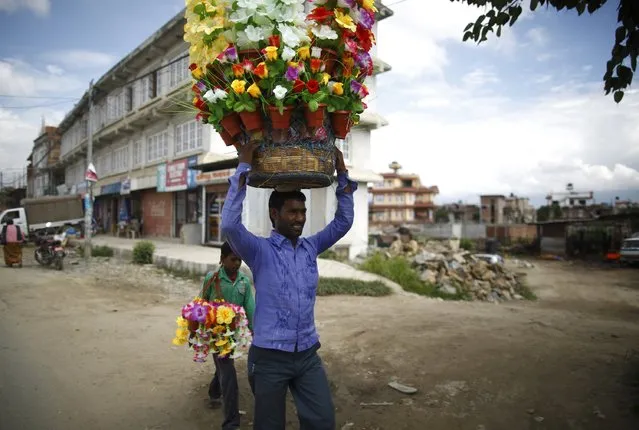 A street vendor carrying plastic flowers walks along the street to sell them in Lalitpur August 18, 2014. (Photo by Navesh Chitrakar/Reuters)