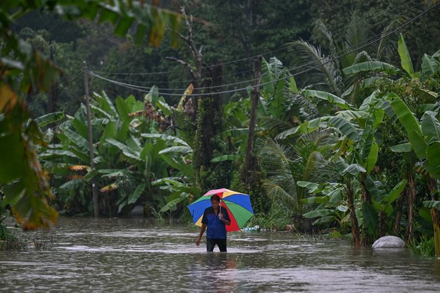 A man walks with an umbrella through flood waters after days of heavy rain in Tumpat in Malaysia's Kelantan state on November 30, 2024. More than 122,000 people have been forced out of their homes as massive floods caused by relentless rains swept through Malaysia's northern states, disaster officials said November 30. (Photo by Mohd Rasfan/AFP Photo)
